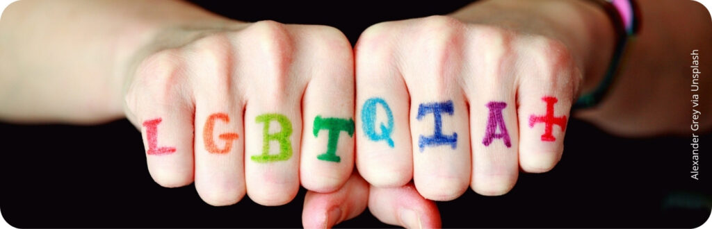 Deux mains closes sur lesquelles sont inscrites les lettres LGBTQIA+